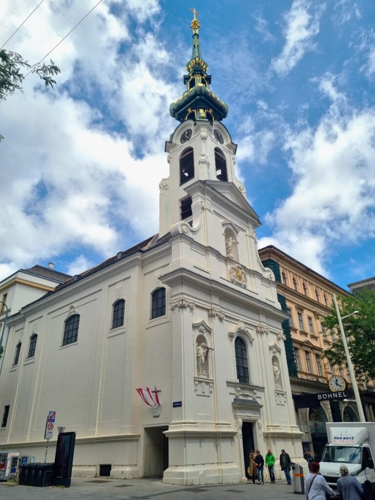 Den Kirchturm der Stiftskirche empfinden viele Wienerinnen und Wiener als einen der schönsten Kirchtürme der Stadt. Das UNO-Denkmal in der Kirche erinnert an Soldaten, die im Auslandseinsatz ums Leben gekommen sind. Foto: © Christian Scherl