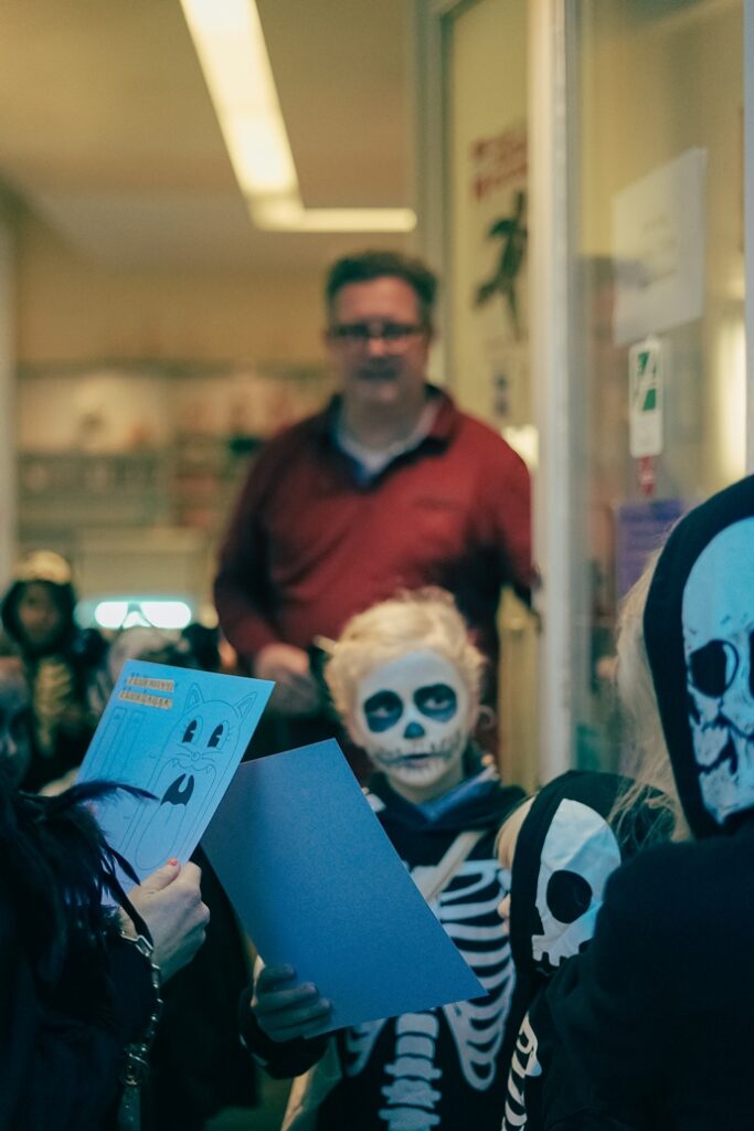 Kinder holen sich die Bastelvorlage für die Halloween-Handpuppen bei froemmel's ab.
