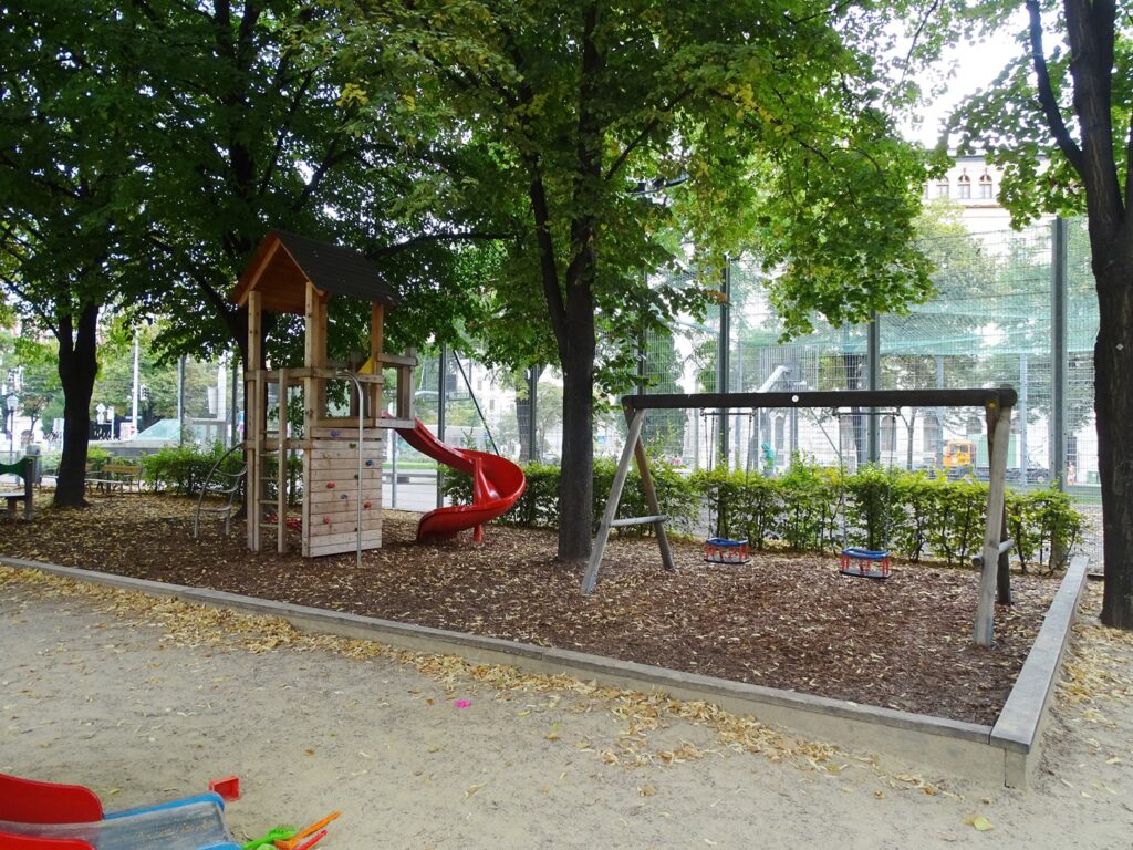 Rutsche, Spielgeräte und im Hintergrund der Ballkäfig im Weghubergpark.