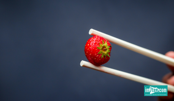 Eine Erdbeere wird nur mit Asiastäbchen angefasst - denn die Erdbeerwoche steht als Synonym für die Menstruation.
